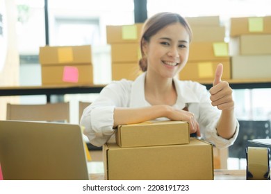 Asian Female Online Business Owner Happy Selling Products Online And Giving Thumb Up Gesture. Woman Showing Doing Good Work At Her Online Business And Showing Thumb Up. Online Business Concept.