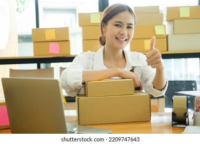 Asian Female Online Business Owner Happy Selling Products Online And Giving Thumb Up Gesture. Woman Showing Doing Good Work At Her Online Business And Showing Thumb Up. Online Business Concept.