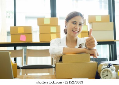 Asian Female Online Business Owner Happy Selling Products Online And Giving Thumb Up Gesture. Woman Showing Doing Good Work At Her Online Business And Showing Thumb Up. Online Business Concept.