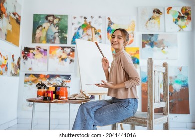 asian female painter painting on canvas in her workshop