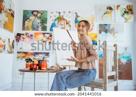 asian female painter painting on canvas in her workshop