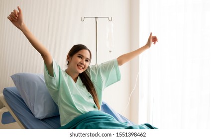 Asian Female Patient Feels Happy And Carefree Durig Resting In A Hospital. Comprehensive Medical Insurance Concept.