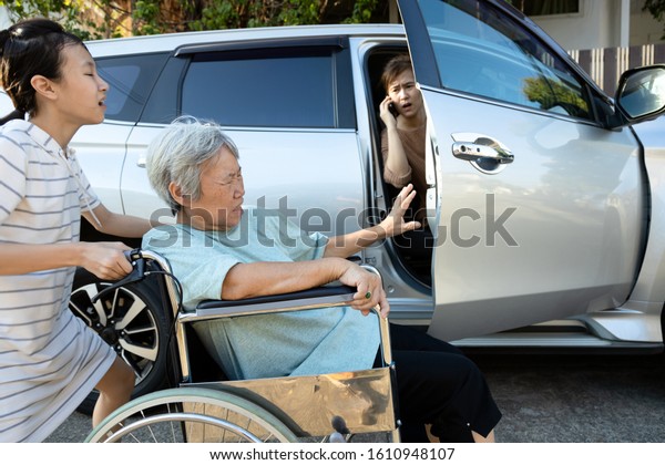 Asian female people enjoy talking on the\
phone,opening the door car slamming the leg of elderly feel\
pain,\
inattentive girl crashed into leg of disabled senior woman\
in wheelchair while open the\
door
