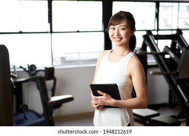 Asian Female Personal Trainer Standing With A Smile In The Training Gym