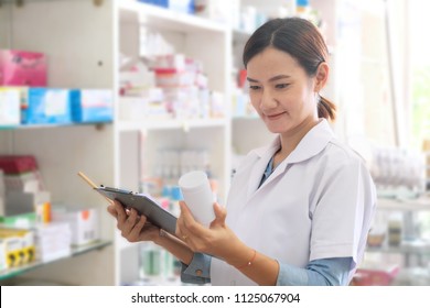 Asian Female Pharmacist Checking Medicine In Drugstore.