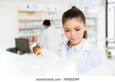 Asian Female Pharmacist Working In Chemist Shop Or Pharmacy