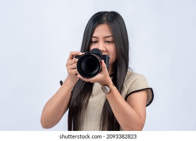 Asian Female Photographer Holding A Pro Camera Standing On A White Back