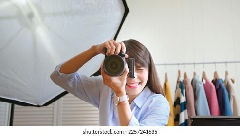 asian female photographer is using digital camera to take portrait pictures in studio - Powered by Shutterstock