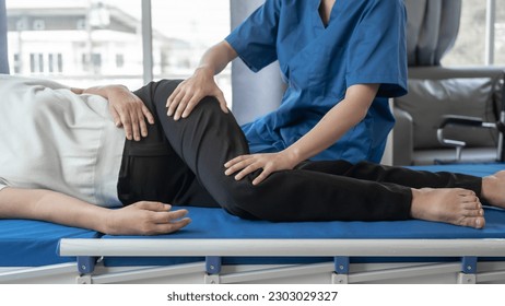 Asian female physiotherapist helping senior older woman stretching hamstring, Rehabilitation physiotherapy, elderly. Causes knee pain, swelling, redness, stiffness in knee, clunking noise in knee. - Powered by Shutterstock