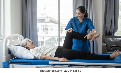 Asian female physiotherapist helping senior older woman stretching hamstring, Rehabilitation physiotherapy, elderly. Causes knee pain, swelling, redness, stiffness in knee, clunking noise in knee. - Powered by Shutterstock