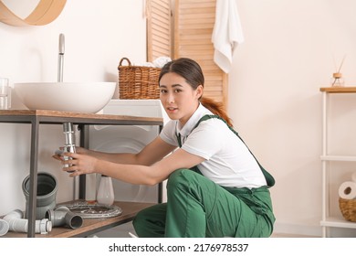 Asian Female Plumber Fixing Sink In Bathroom