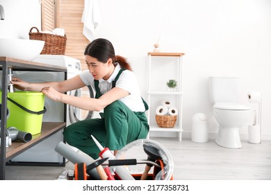 Asian Female Plumber Fixing Sink In Bathroom