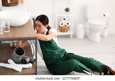 Asian Female Plumber Fixing Sink In Bathroom