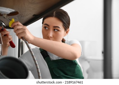 Asian Female Plumber Fixing Sink In Bathroom