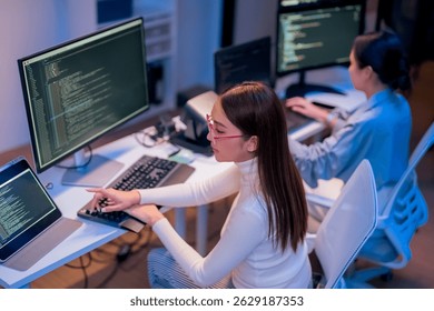 asian female programmer sits a dark tech workspace at night, fully focused on developing an online project. She writes HTML scripts and code for a modern website while contributing to automation work