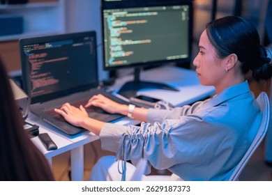 asian female programmer sits a dark tech workspace at night, fully focused on developing an online project. She writes HTML scripts and code for a modern website while contributing to automation work
