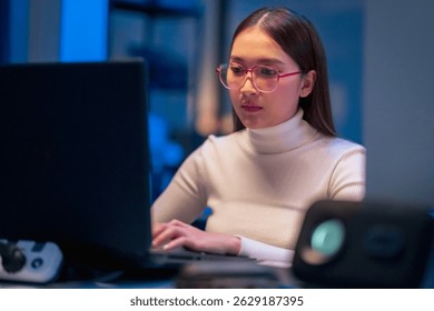 asian female programmer sits a dark tech workspace at night, fully focused on developing an online project. She writes HTML scripts and code for a modern website while contributing to automation work