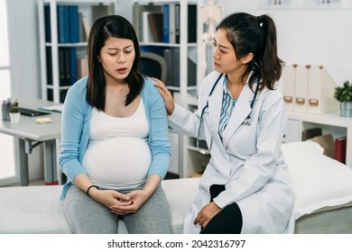 asian female psychologist doctor is keeping hand on the depressed pregnant patient who is talking with a worried face expression on treatment bed in the clinic. - Powered by Shutterstock