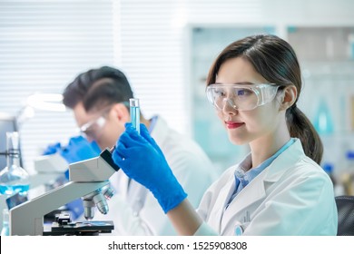 asian female scientist hold a test tube filled with liquid in the laboratory - Powered by Shutterstock