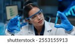 Asian female scientist holds a test tube filled with blue liquid in the laboratory. Examination. Medical research. Drug experiment. Medical science research concept.