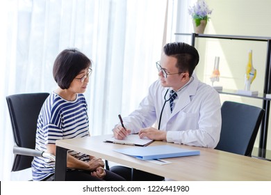 Asian female senior elderly patient woman talking explain illness consultation with a medical doctor man in office, healthy care and medical concept - Shutterstock ID 1226441980