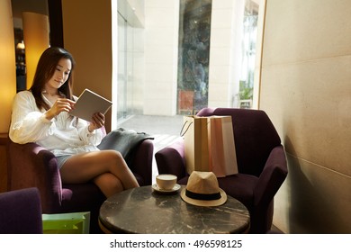 Asian female shopaholic resting in cafe with tablet computer - Shutterstock ID 496598125