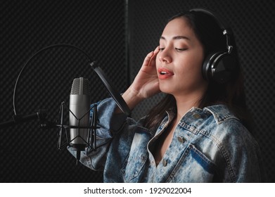 Asian Female Singer With A Passion For Music And Microphone. While Singing Recorded In A Professional Studio Music Concept