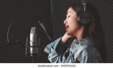 Asian Female Singer With A Passion For Music And Microphone. While Singing Recorded In A Professional Studio Music Concept