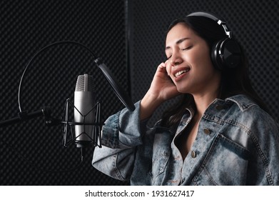 Asian Female Singer With A Passion For Music And Microphone. While Singing Recorded In A Professional Studio Music Concept