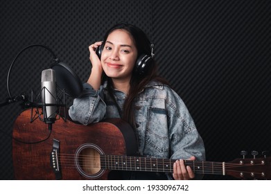 Asian Female Singer With A Passion For Music And Microphone. While Playing Her Guitar In A Professional Studio. Music Concept, Sound Recording Concept.