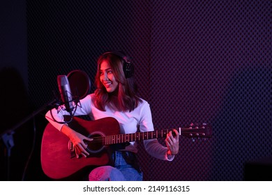 Asian Female Singer Playing Guitar And Recording In The Studio.