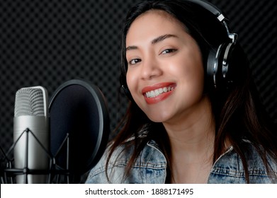 Asian Female Singer Singing In A Recording Studio. Female Singer Singing And Playing Guitar.