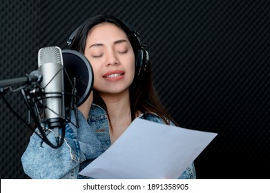 Asian Female Singer Singing In A Recording Studio. Female Singer Singing And Playing Guitar.