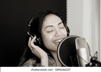 Asian Female Singer Singing In A Recording Studio. Female Singer Singing And Playing Guitar.