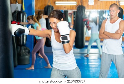 Asian Female Sportsman Boxer Practicing Different Punches With Boxing Bag At Gym