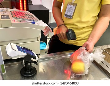 Asian female staff scanning product barcode at cash counter in supermarket.  - Powered by Shutterstock