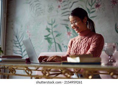 An asian female student is doing her assignment on a laptop while sitting in a coffee shop. - Shutterstock ID 2154959261