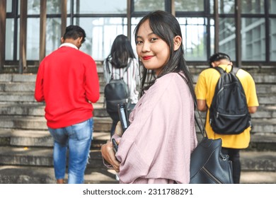 Asian female student glancing back while going for a class in college. Girl walking with friends going for class in school. - Shutterstock ID 2311788291