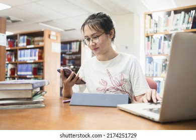 Asian female student in the library using a smartphone. - Shutterstock ID 2174251729