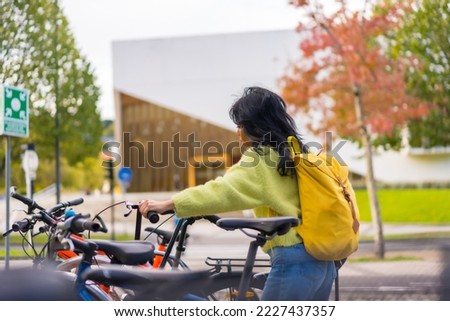 Asian female student parking the bike in college campus, healthy and green life