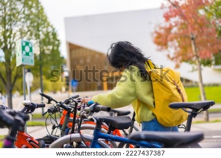 Asian female student parking the bike in college campus, healthy and green life