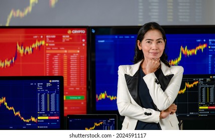 Asian Female Successful Professional Broker Trader Investor Stand Smile Crossed Arm Hold Hand On Chin Look At Camera In Front Computer Monitors With Bitcoin Cryptocurrency Stock Graph Chart Analysis.