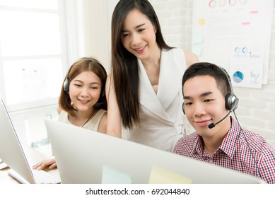 Asian Female Supervisor Discussing Work With Telemarketing Customer Service Agent Team In Call Center