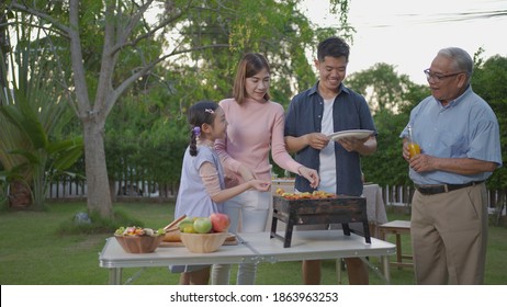 Asian female take BBQ food party summer grilling meat. Happy family enjoying meal together. People having outdoor party eating food at backyard home in garden. - Powered by Shutterstock