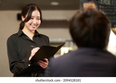 Asian female taking an order at a restaurant