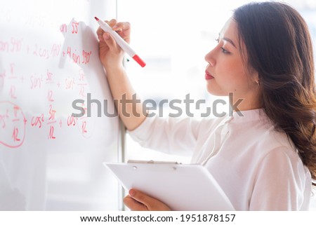 The Asian female teacher is rewriting the lecture on the board
