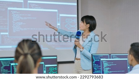 asian female teacher is speaking in adult education class with slides on computer screen - students sitting on chair using pc learning programming