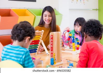 Asian Female Teacher Teaching Mixed Race Kids Play Toy In Classroom,Kindergarten Pre School Concept