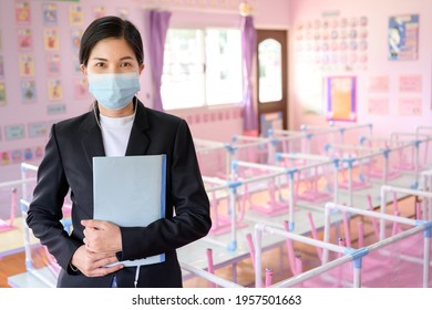 Asian Female Teacher Wearing Mask To Prevent Spread Of COVID 19 In Classroom Without Students While Waiting For The School To Reopen