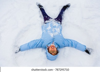 Asian Female Teenager Enjoying Herself Making Snow Angel On A Cold Winter Day In Japan